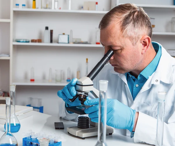 प्रयोगशाळा मध्ये सूक्ष्मदर्शक वापरून पुरुष वैज्ञानिक संशोधक . — स्टॉक फोटो, इमेज