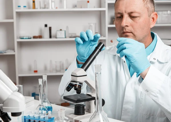 erkek bilimsel araştırmacı laboratuarda mikroskop kullanarak.
