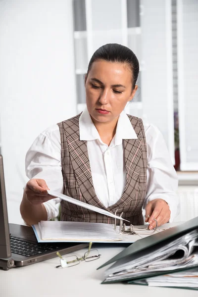Молодая предпринимательница, сидящая на рабочем месте и работающая с бумагами — стоковое фото