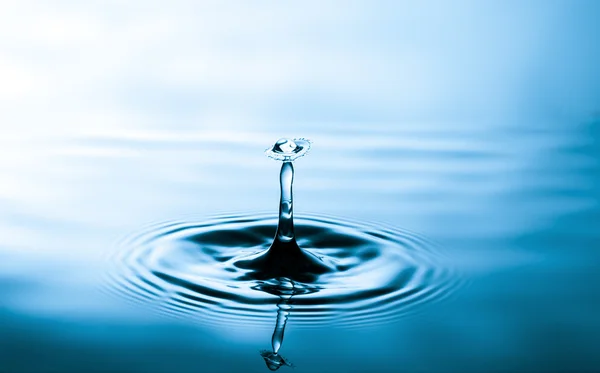 Droplet falling in blue water — Stock Photo, Image