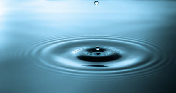 Droplet falling in blue water — Stock Photo, Image