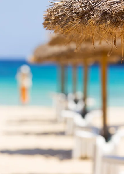 Strohschirme und Liegen am Sandstrand. — Stockfoto