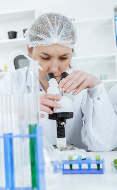Kadın bilim adamı bir laboratuarda mikroskop ile çalışma