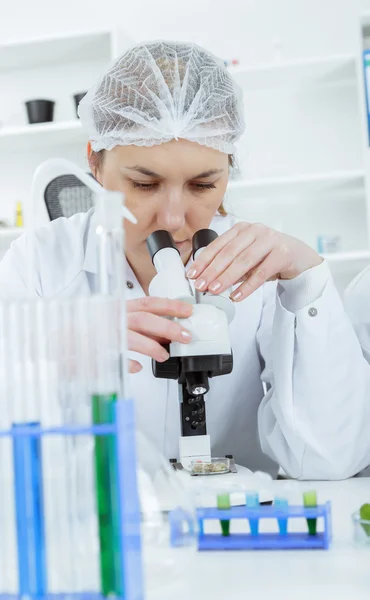 Mujer científica trabajando con un microscopio en un laboratorio — Foto de Stock