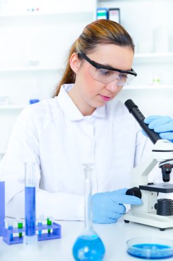 bir laboratuarda mikroskop ile çalışan kadın