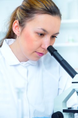 bir laboratuarda mikroskop ile çalışan kadın