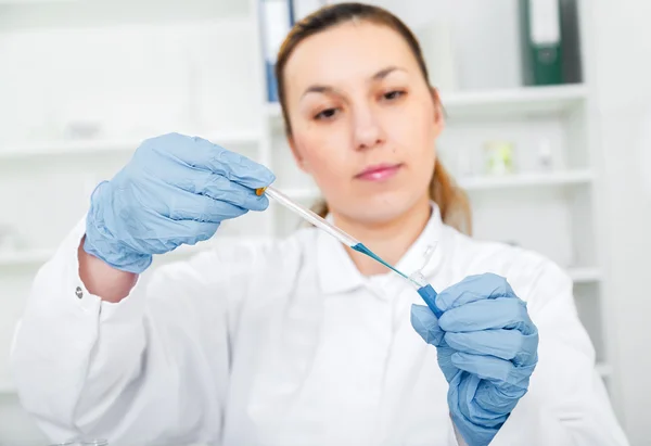 Pesquisador fêmea com equipamento de vidro no laboratório foco suave em vidro e mãos . — Fotografia de Stock