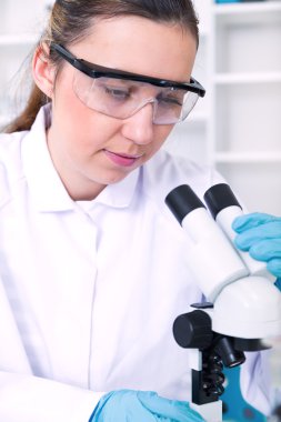 bir laboratuarda mikroskop ile çalışan kadın