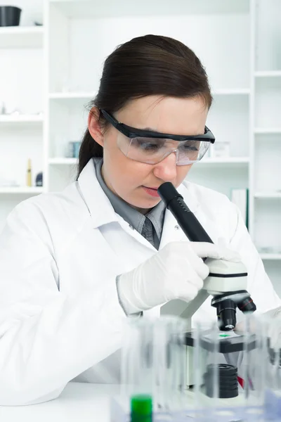 Mulher trabalhando com um microscópio em um laboratório — Fotografia de Stock