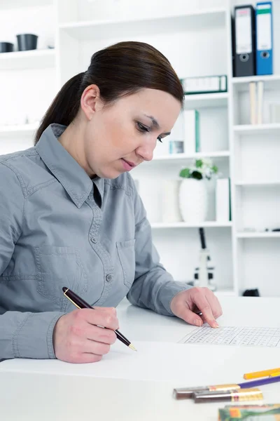 Young business woman reading sitting at the desk on office background — Stock Photo, Image