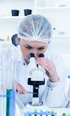 bir laboratuarda mikroskop ile çalışan kadın