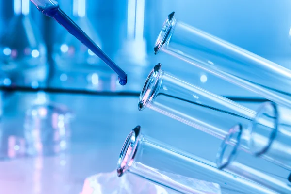 Pipette, die einem von mehreren Reagenzgläsern Flüssigkeit zufügt.. — Stockfoto