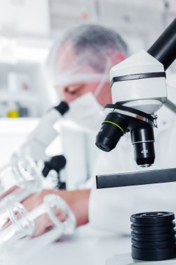 koruyucu maske, laboratuvarda çalışan bilim adamı inceliyor bir sıvı ile .