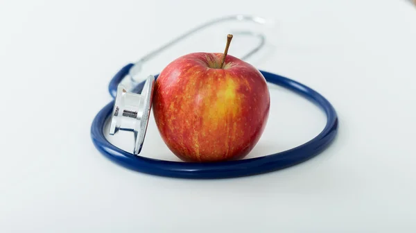 Rött äpple och stetoskop på vit bakgrund. — Stockfoto