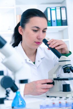 Bir laboratuarda mikroskop ile çalışan kadın. Tonlama resim