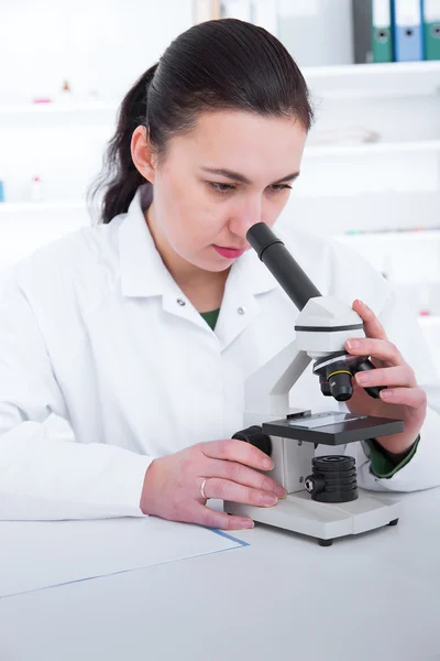 Kobieta pracuje pod mikroskopem w laboratorium. Tonowanie obrazu — Zdjęcie stockowe