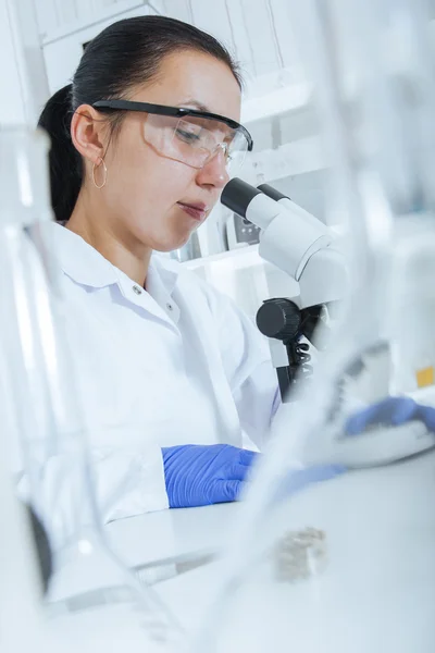 Женщина, работающая с микроскопом в лаборатории . — стоковое фото