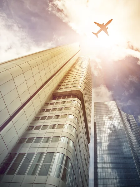 Vliegtuig vliegt over moderne office wolkenkrabbers — Stockfoto