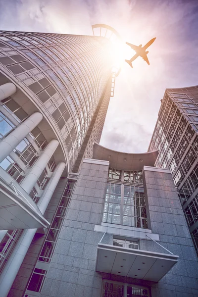 Avión volando sobre rascacielos de oficina moderna — Foto de Stock