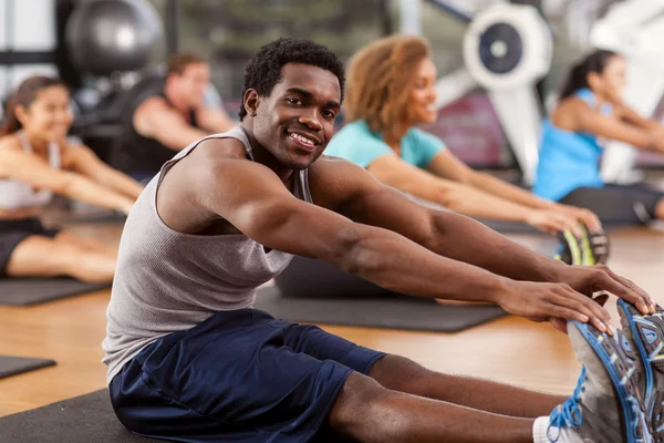 Young African-American man stretching in a gym — Stock Photo, Image
