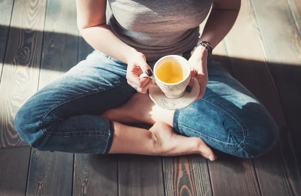 Gemütliches Foto einer jungen Frau mit einer Tasse Tee auf dem Fußboden sitzend — Stockfoto