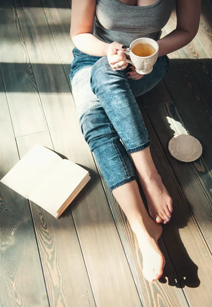 Cozy photo of young woman with cup of tea sitting on the floor — Stock Photo, Image
