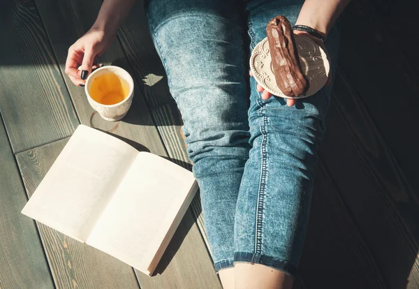 Gezellige foto van een jonge vrouw met thee en cake zittend op de vloer — Stockfoto