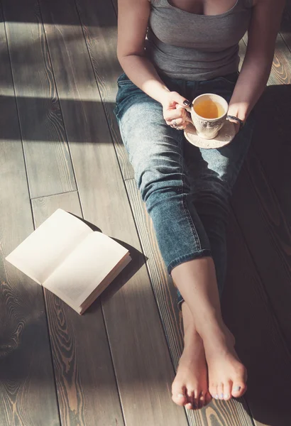 Cozy photo of young woman with cup of tea sitting on the floor — Stock Photo, Image