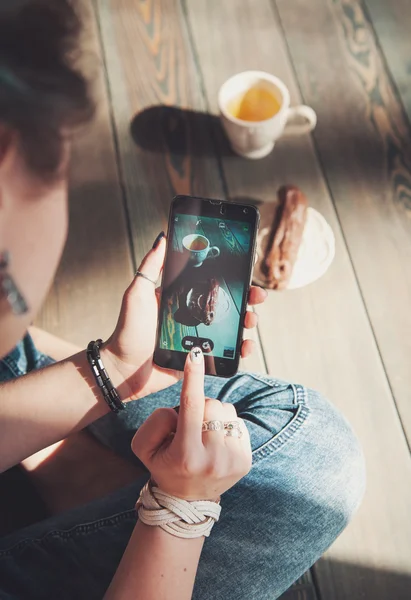 Mão de mulher com smartphone tirando foto de comida de chá e bolo — Fotografia de Stock
