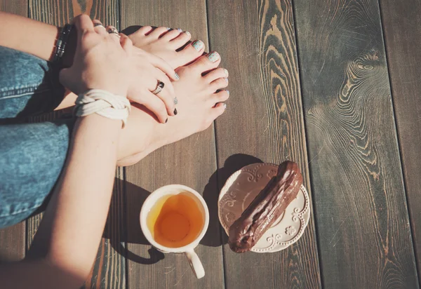 Accogliente foto di piedi di giovane donna con tè e torta sul pavimento — Foto Stock