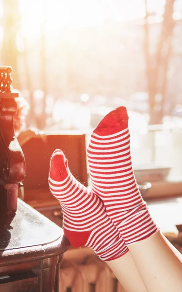 Frauenfüße in roten Socken am Fenster — Stockfoto