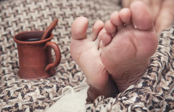 Homme pieds sur plaid de laine et tasse de café — Photo