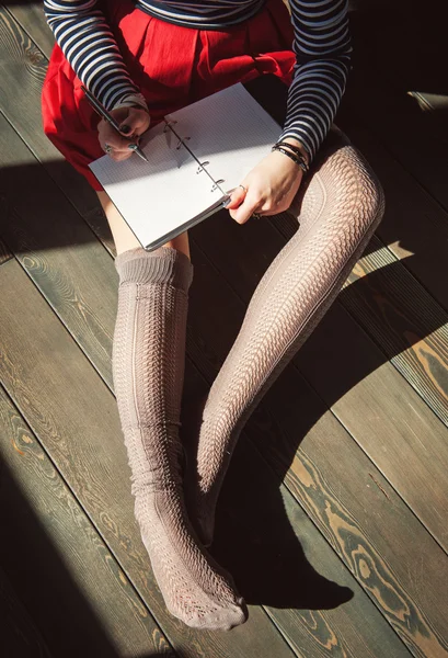 Cozy photo of young woman writing in notebook sitting on the flo — Stock Photo, Image