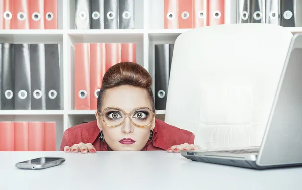 Mujer de negocios con grandes ojos escondidos detrás de la mesa — Foto de Stock