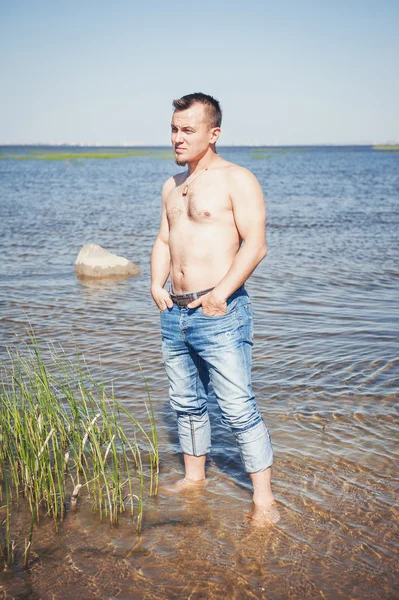 Stilig man med naken överkropp står i havet — Stockfoto