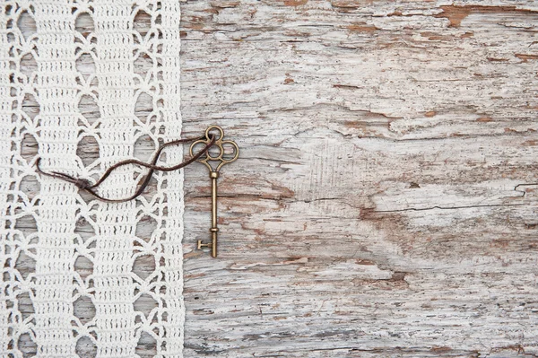 Vintage bakgrund med gammal nyckel och spets på oförskämd trä — Stockfoto