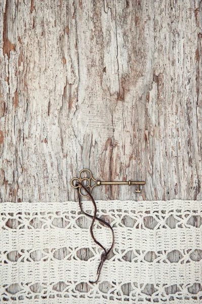 Fondo vintage con llave vieja y encaje en la grosera madera — Foto de Stock