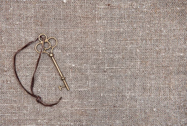 Вінтажний фон зі старим ключем на мішковині — стокове фото