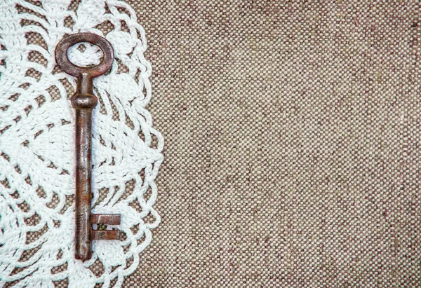 Vintage sfondo con pizzo e vecchia chiave su texture iuta — Foto Stock