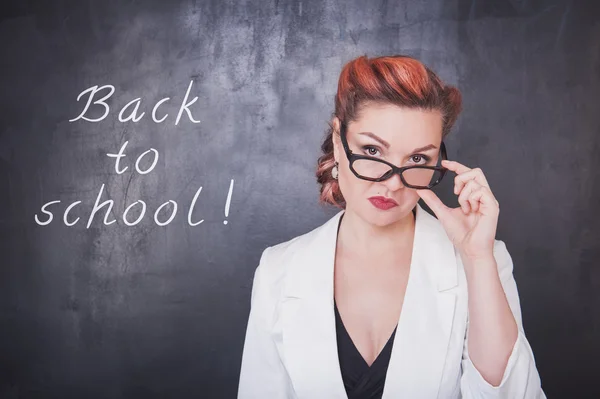 Serious teacher in glasses on blackboard background — Stock Photo, Image