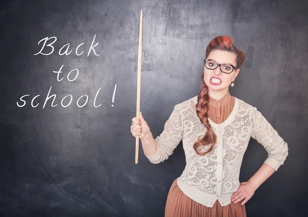 Angry teacher with pointer on blackboard background — Stock Photo, Image