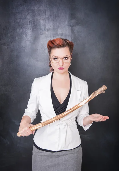 Strict teacher with wooden stick on blackboard background — Stock Photo, Image