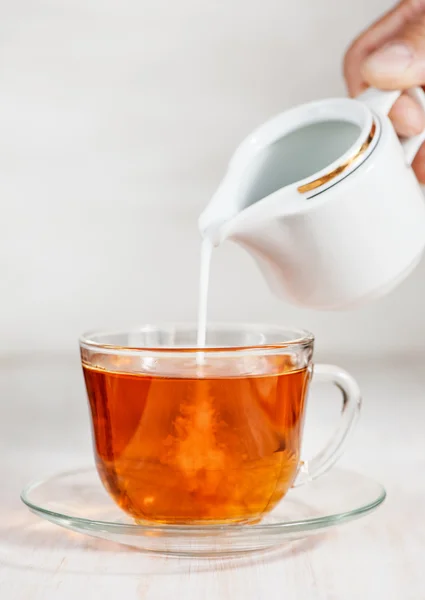 Leite derramado em xícara de chá — Fotografia de Stock