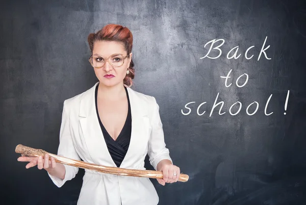 Angry teacher with wooden stick on chalkboard — Stock Photo, Image