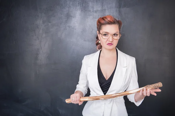 Angry teacher with wooden stick on blackboard — Stock Photo, Image