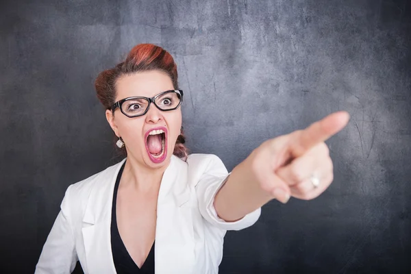 Wütend schreiende Frau zeigt auf Tafel-Hintergrund — Stockfoto