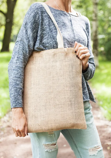 Mujer sosteniendo bolsa de lona vacía. Plantilla maqueta arriba —  Fotos de Stock