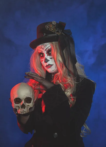 Beautiful woman with scary Halloween make up dead day calavera style with skull on blue smoke backgroun