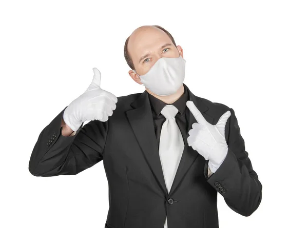 手術用の医療用ウイルス保護マスクを持っているハンサムな若いビジネスマンとともに白い手袋上で隔離された親指を示す — ストック写真
