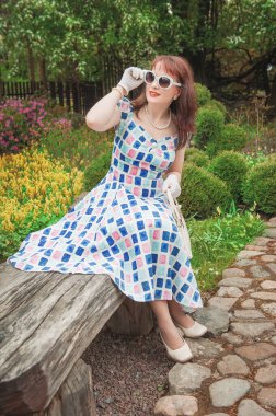 Dışarıda gözlüklü, retro tarzı elbiseli güzel bir kadın.